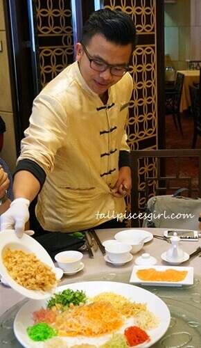 Waiter pours the ingredients onto the Yee Sang as he utters auspicious phrases
